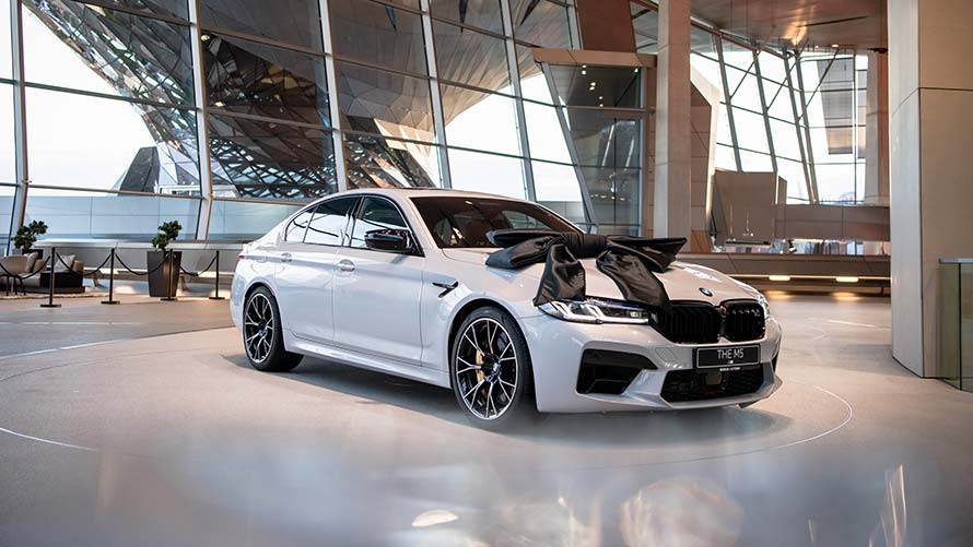 White BMW M5 with black bow on the pickup platform of BMW Welt