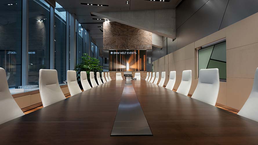 View into conference room with large table and white seating in Business Club of BMW Welt