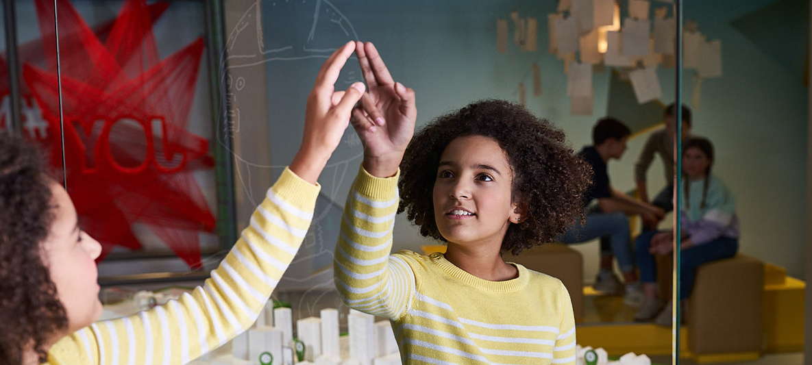 Child looks in mirror in front of large city model in BMW Campus workshop 