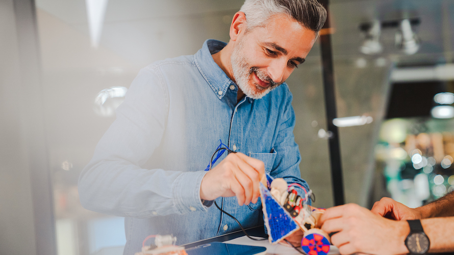 Firmenworkshops Future Mobility Mann lötet selbstgebautes Automodell aus Holz und Motorisierung