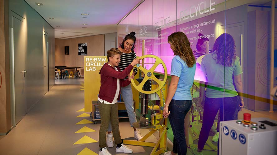 Kind dreht Rad an einer Maschine im BMW Nachhaltigkeits-Workshop