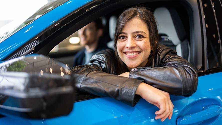 Share Now BMW Smiling woman leans out of a blue BMW from Share Now